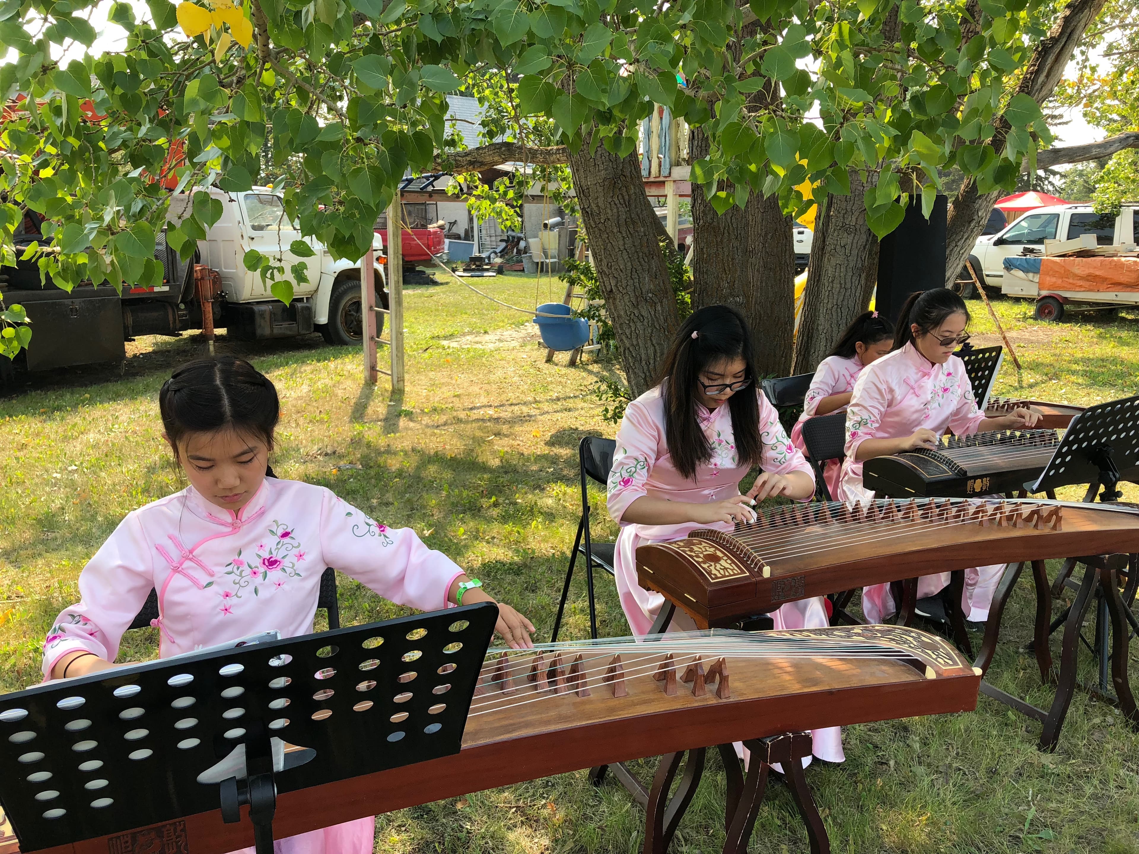 Students performing guzheng outdoors at a community event